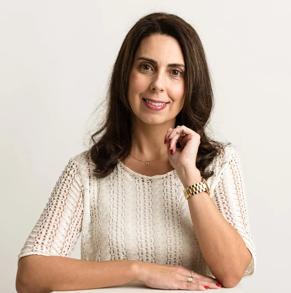 Ana Paula Becker, psicóloga clínica, sentada e sorrindo em retrato profissional
